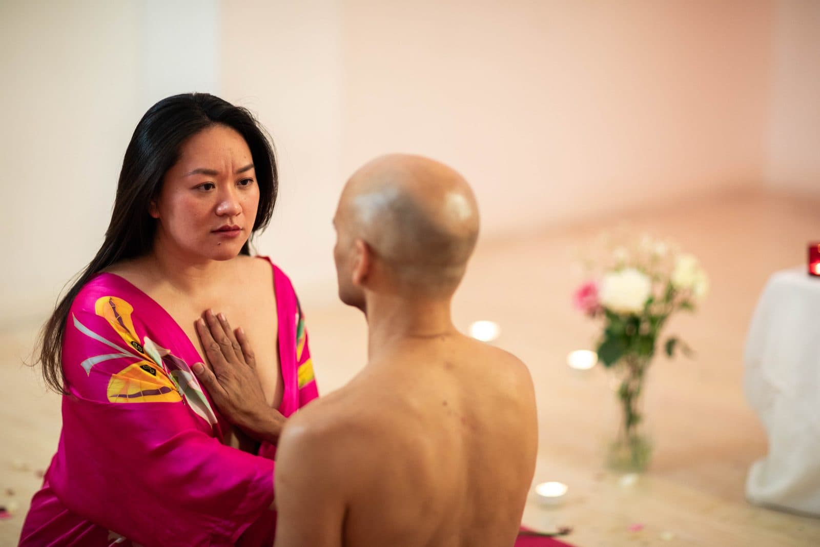 A woman and a man sitting face to face, her hand resting on his heart