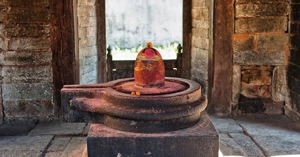 A traditional stone Shivalingam shrine with offerings